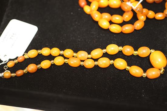 A single strand graduated oval amber necklace with yellow paste spacers, 15.5in.